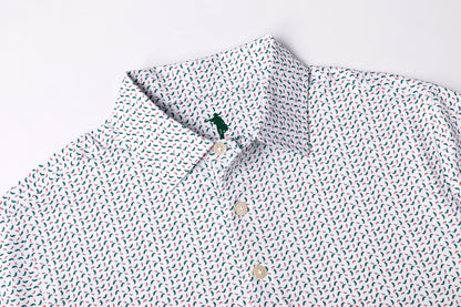 A close-up of a white button-down shirt with a dense, small-scale multicolor print of red, blue, and green motifs, featuring a classic collar and a small green embroidered polo player logo on the inner neck label.