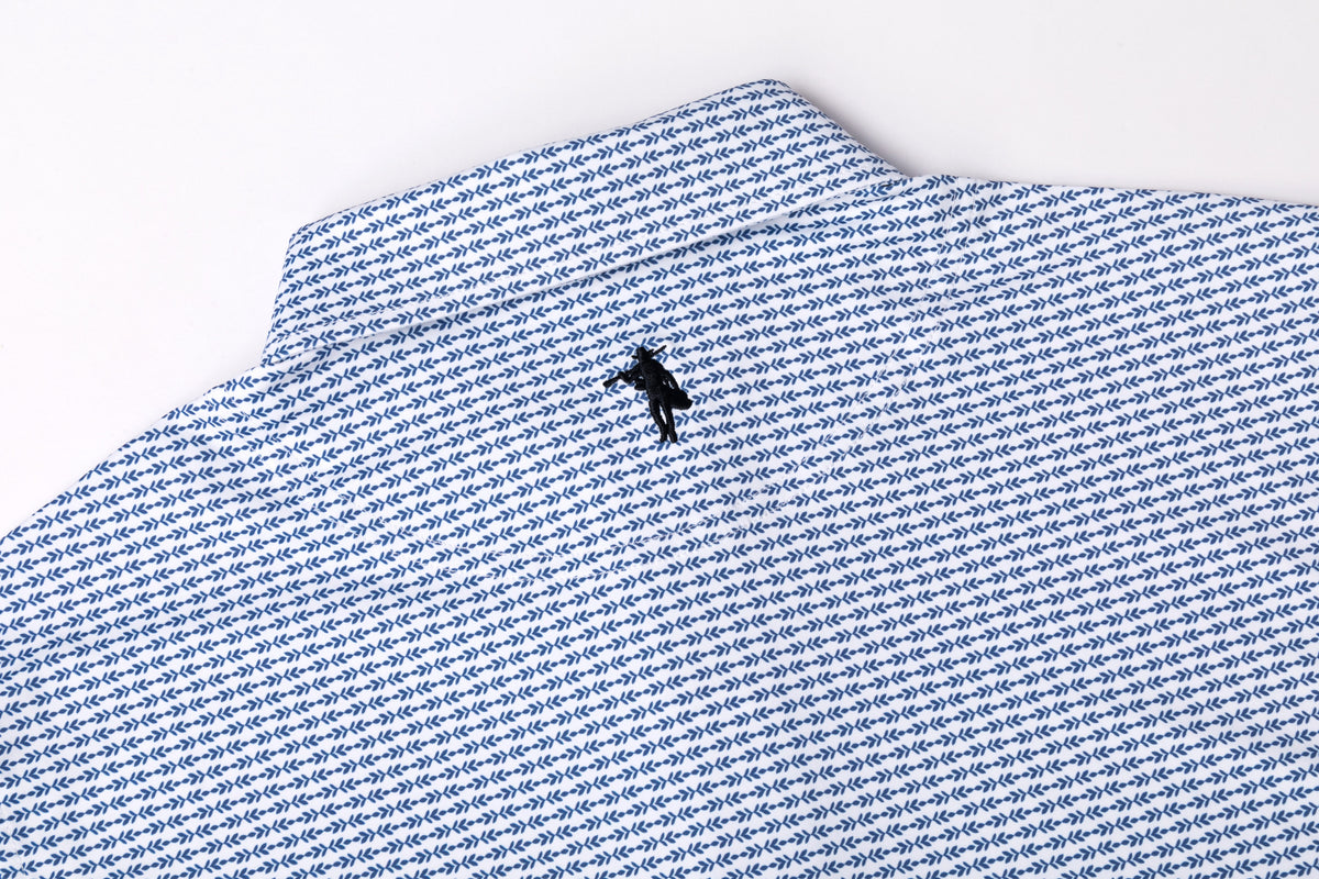 Close-up of a blue and white micro-patterned collared shirt with a small black embroidered polo player logo on the chest, set against a plain white background.