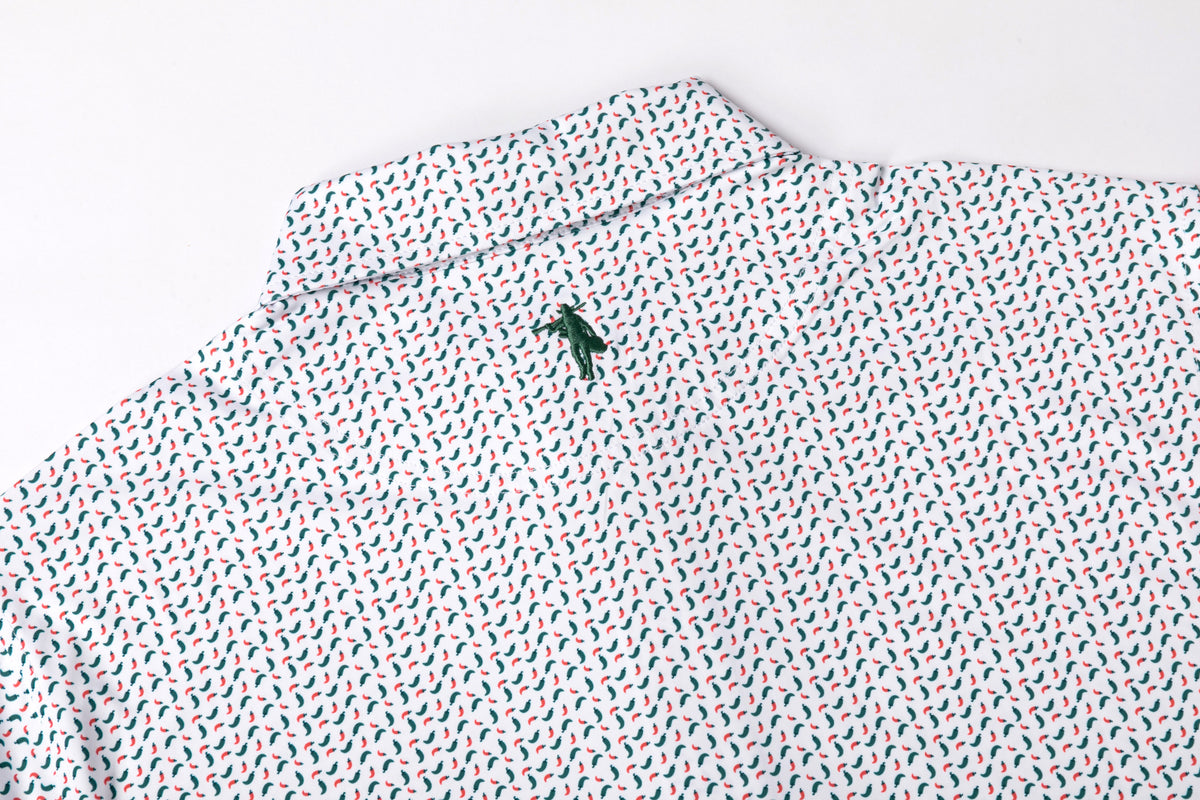 A close-up of a white collared shirt with a repeating small red and blue leaf pattern and a small green embroidered logo on the collar.