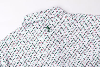 A close-up of a white collared shirt with a repeating small red and blue leaf pattern and a small green embroidered logo on the collar.