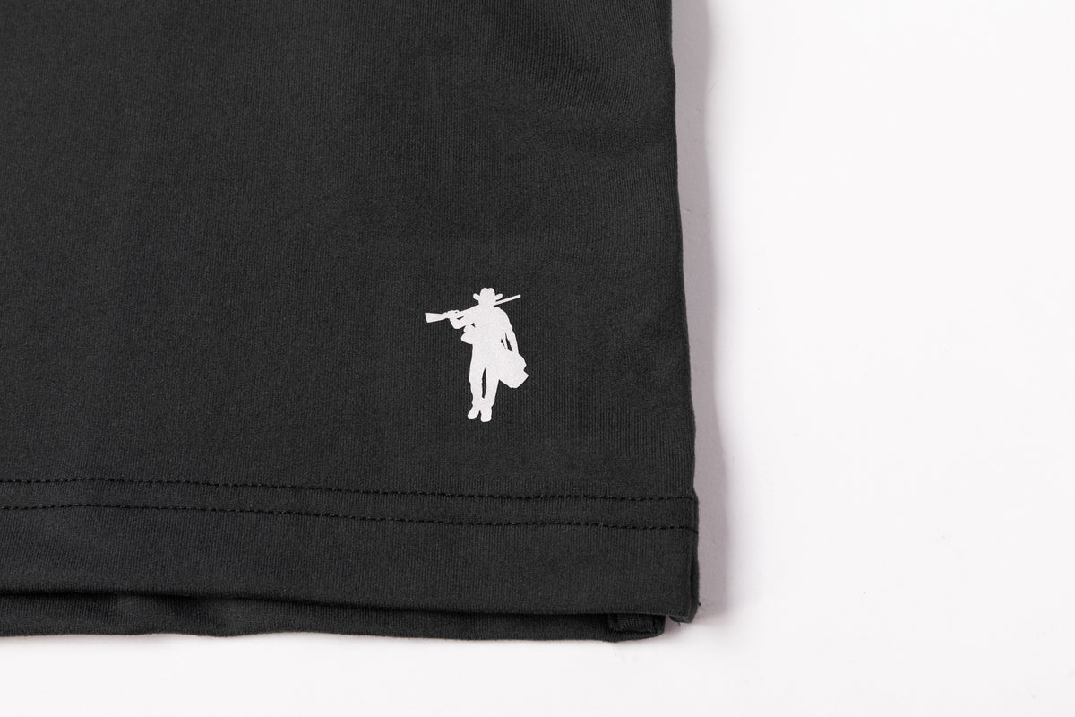 Close-up of a black garment corner with a small white embroidered cowboy silhouette logo on the left side, set against a plain white background.
