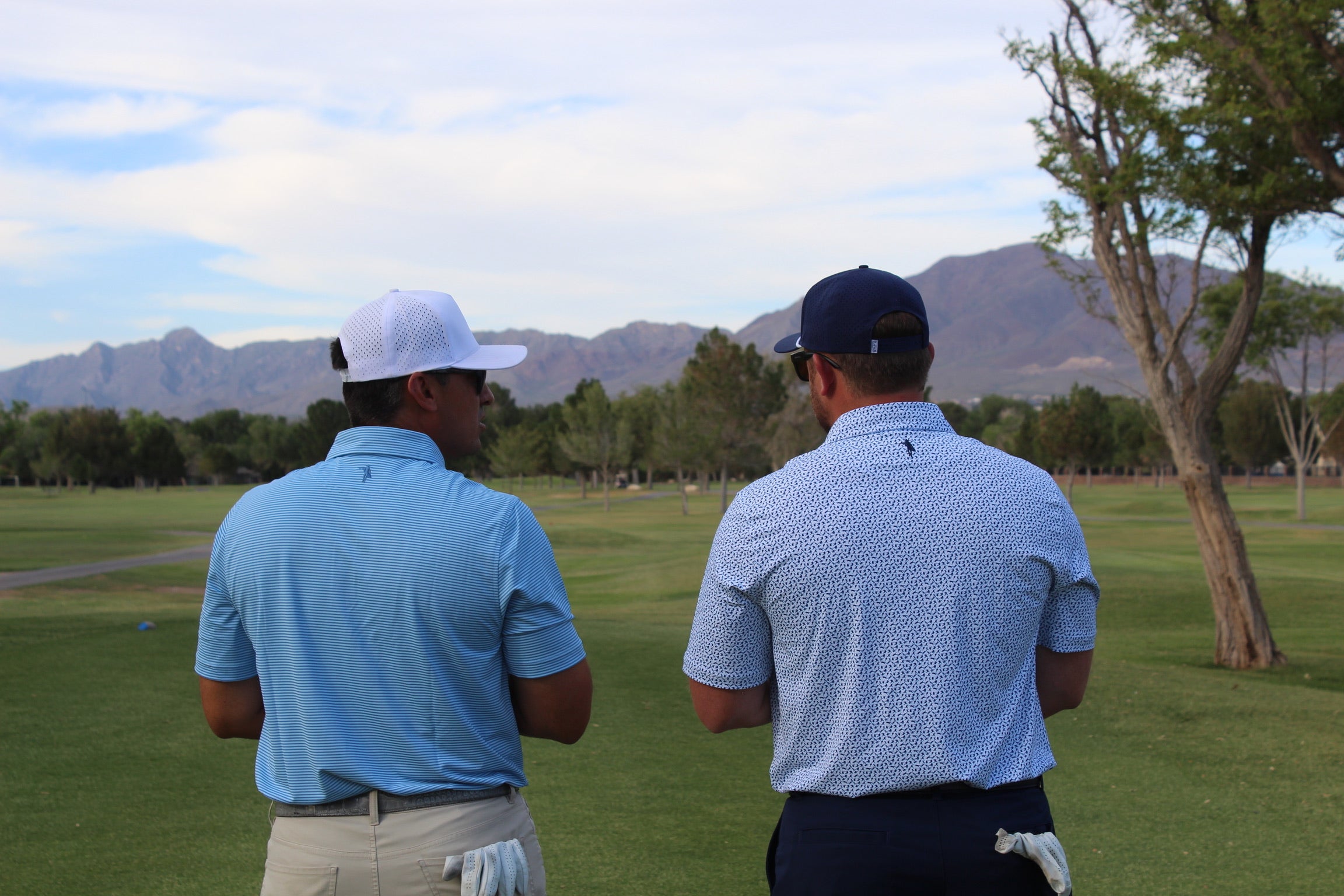 Two golfers looking over a tee box, talking
