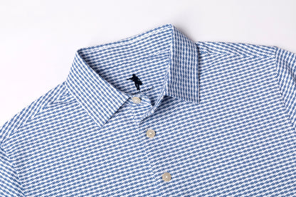 Close-up of a blue and white micro-patterned button-down shirt collar with white buttons, laid flat on a white background.