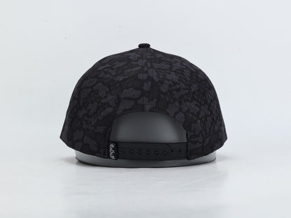 Black snapback cap with a subtle tonal camouflage pattern, shown from the back on a light gray background.