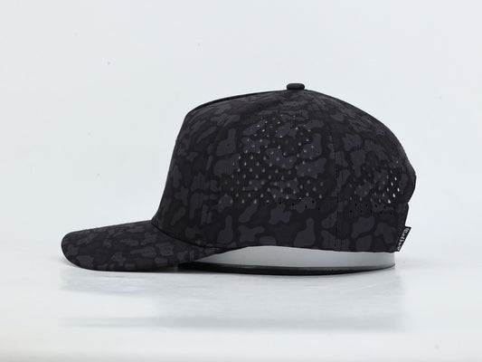 A black baseball cap with a subtle tonal camouflage pattern, featuring perforated side panels for ventilation and a white curved brim underside, shown against a plain white background.